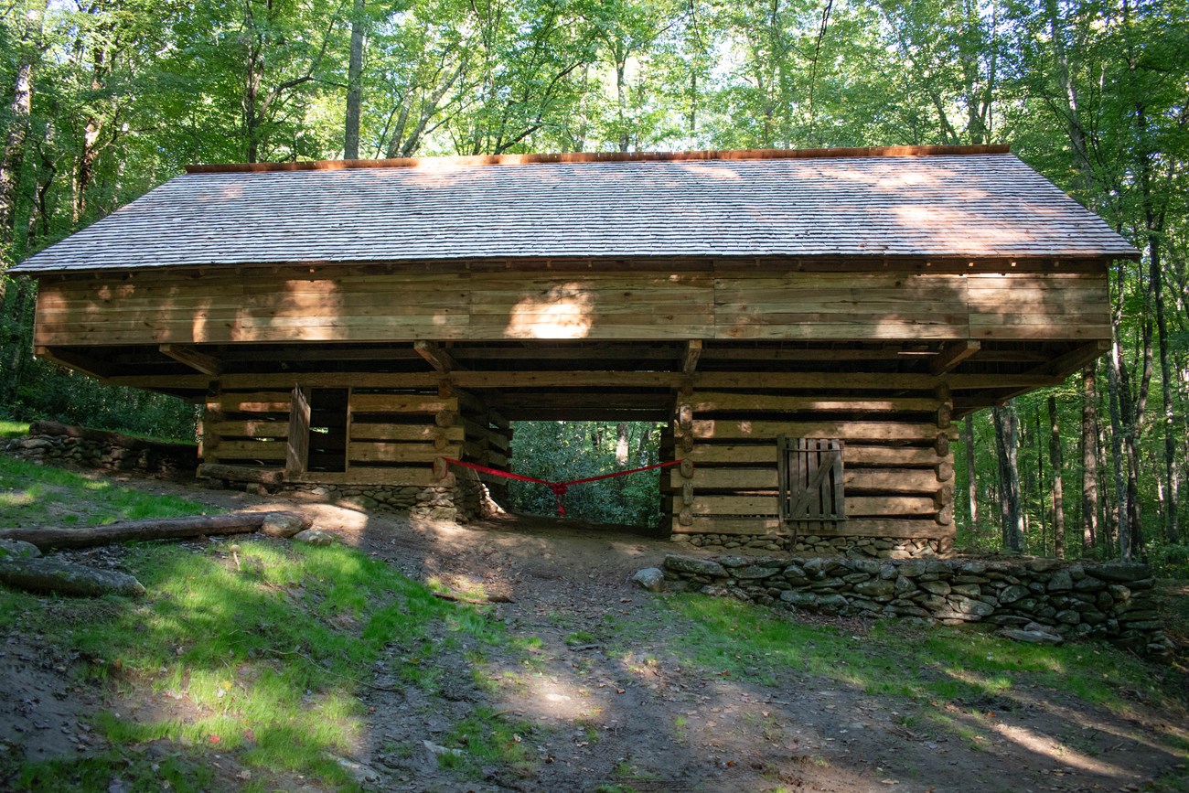 A newly-constructed cantilever barn in the forest with a red ribbon draped across the front.