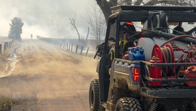 An ATV traveling down a dirt road that is smoke covered.