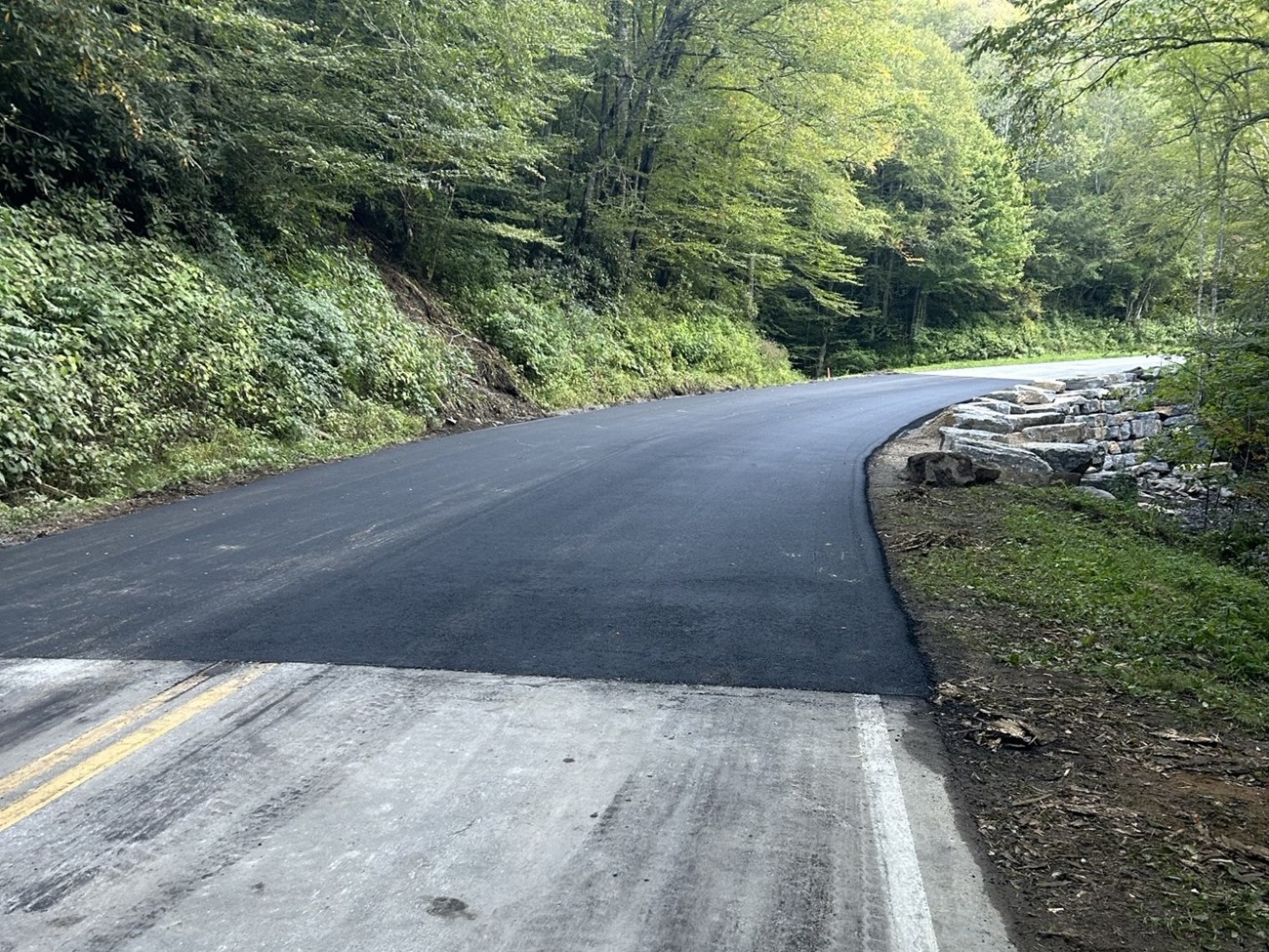 A new paved section of roadway in the forest.