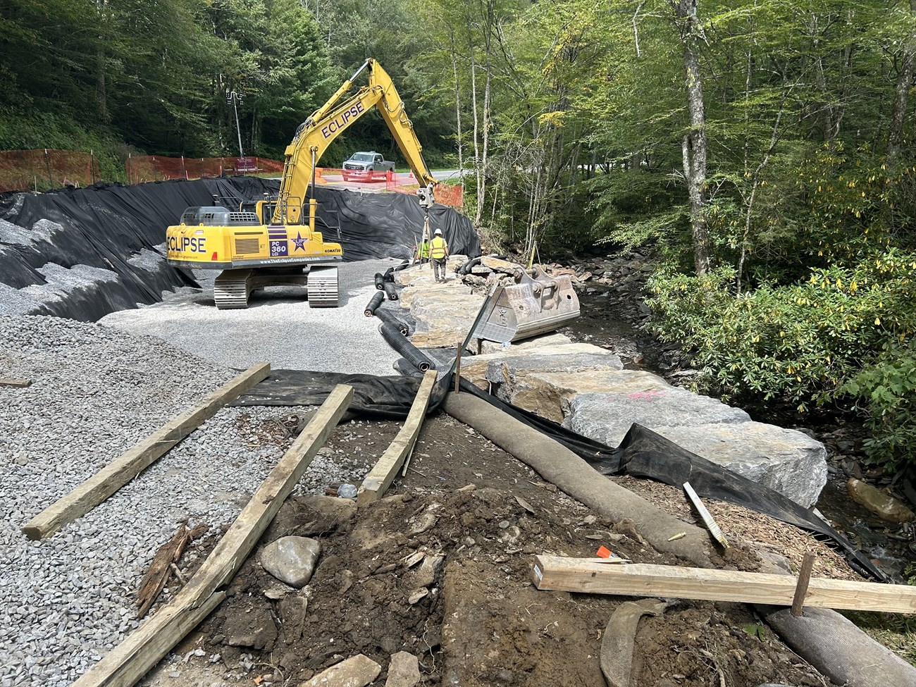 Crew in a construction site building up a roadway in the forest.