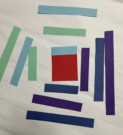 Strips of paper in shades of purple, green, and blue around a red square.