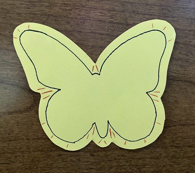 A cut out of a butterfly on a table with pencil marks around it.