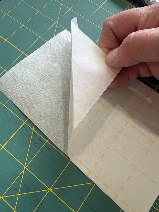 A person's hand pulling apart two pieces of white fabric.