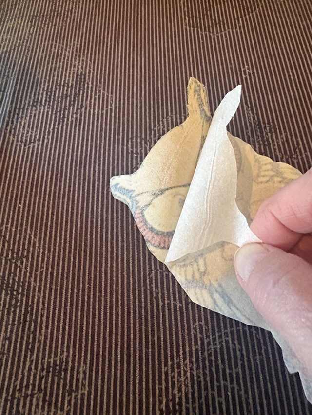 An owl fabric cut out being peeled into two pieces.