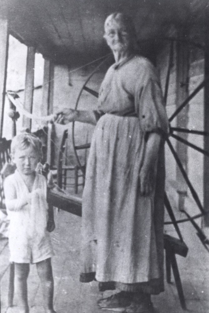 A woman stands at a spinner with a child.