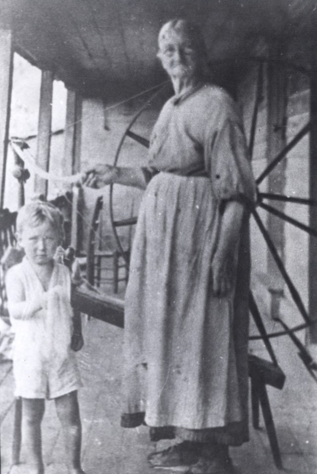 A woman stands at a spinner with a child.