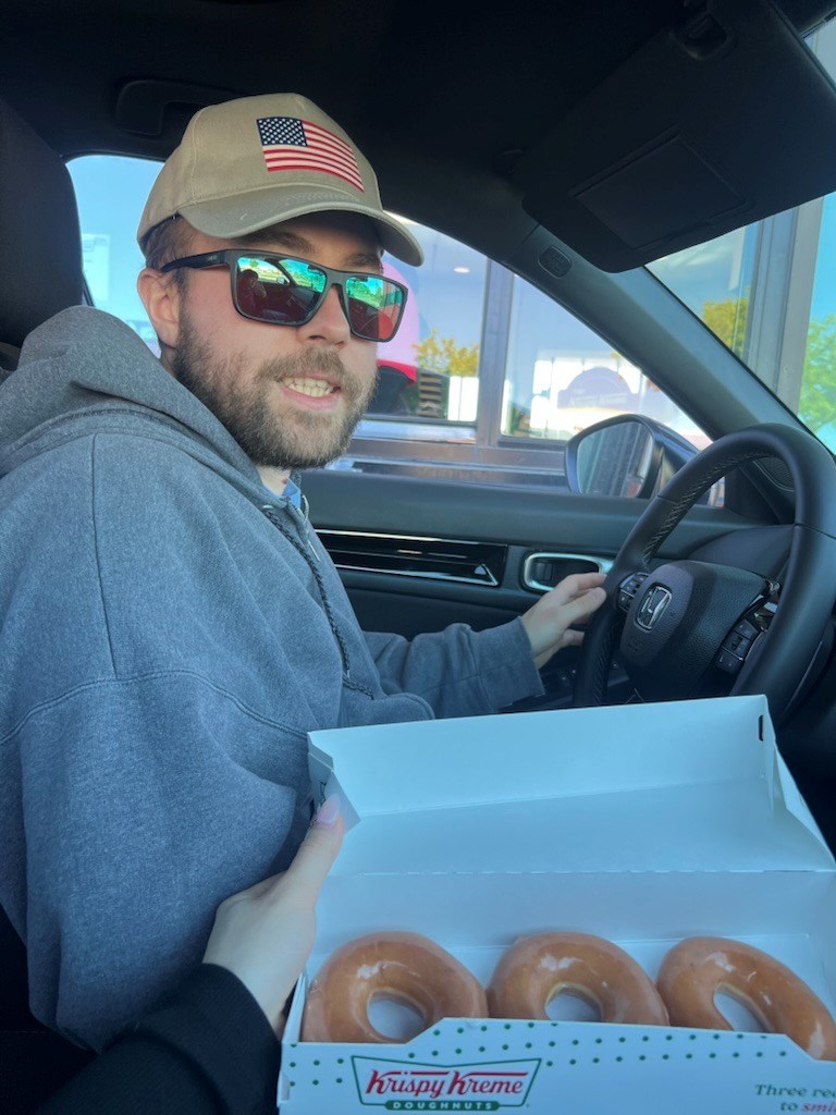A man in a car with some donuts.