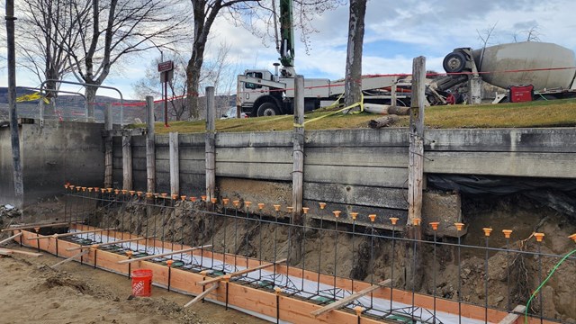 Concrete is ready to be poured at the base of a wooden fence.