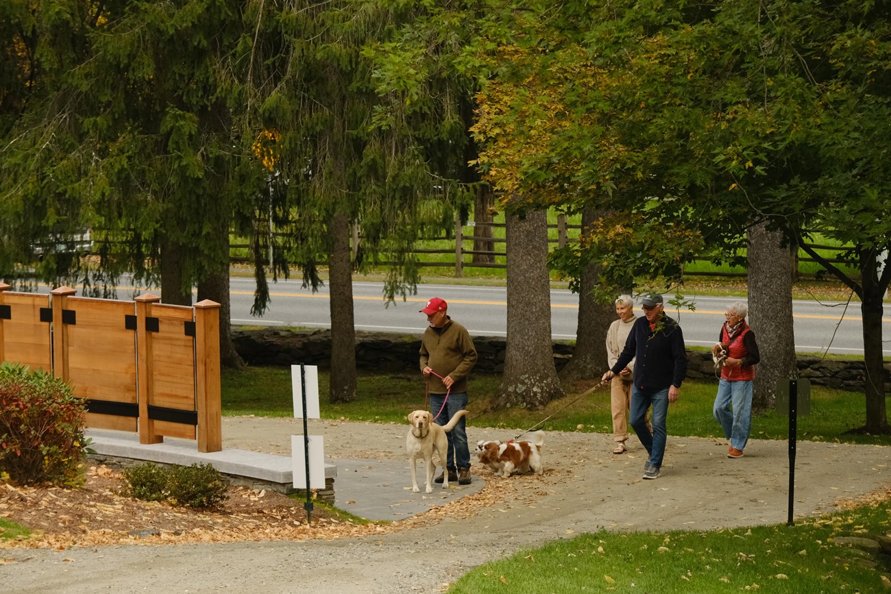 group of visitors and dogs on leash walk into park entrance