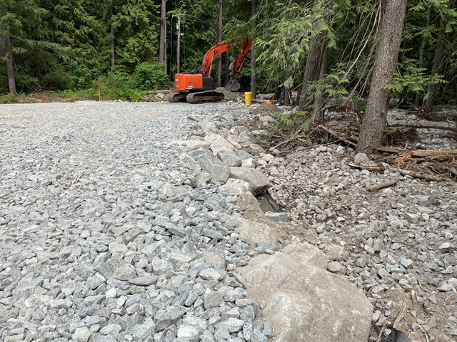 an orange excavator works on a gravel road in a forest