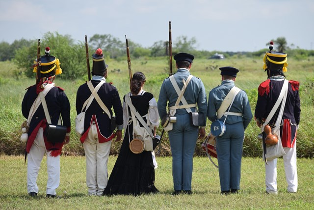 Volunteers dressed in historic attire prepare to demonstrate historic weapons.