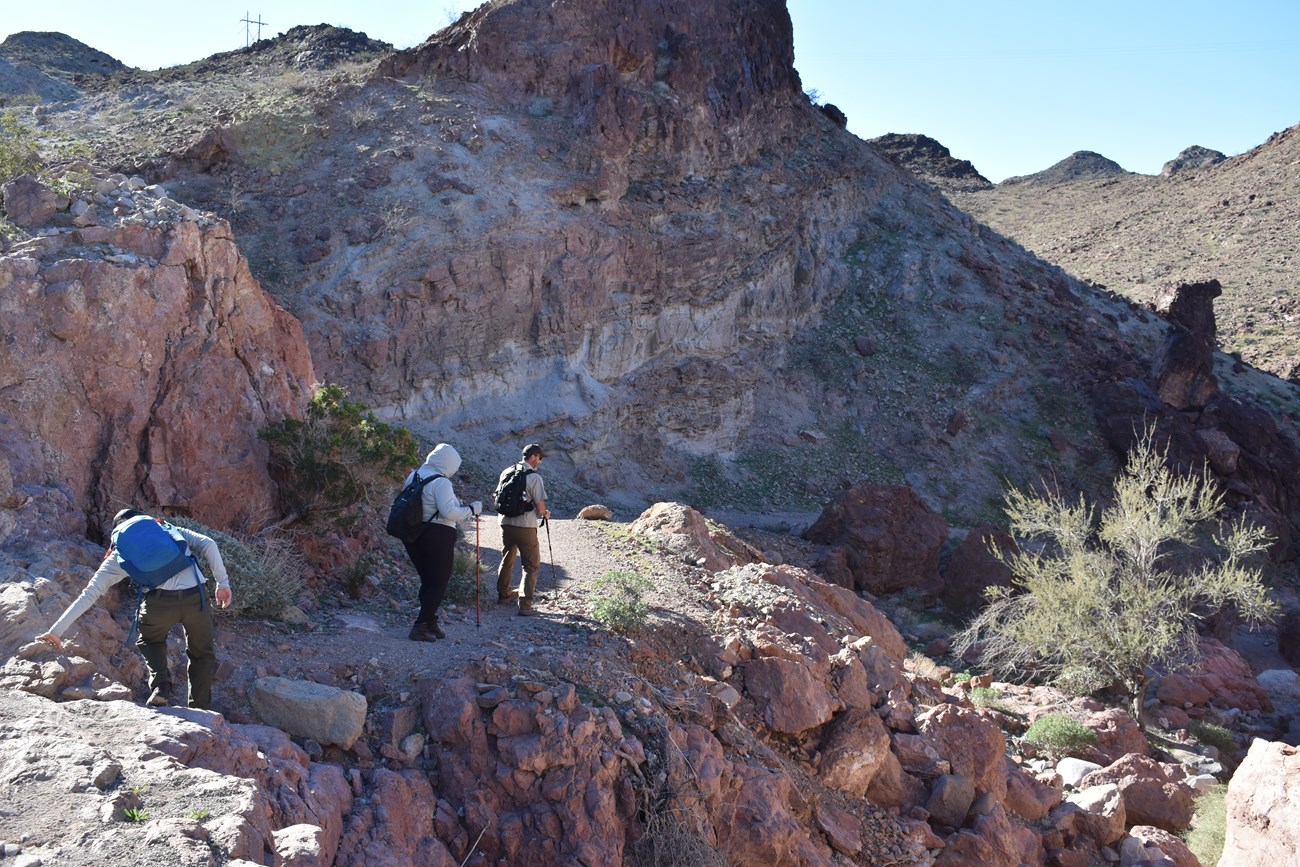 Rangers and a volunteer hiking down the rocky terrain.