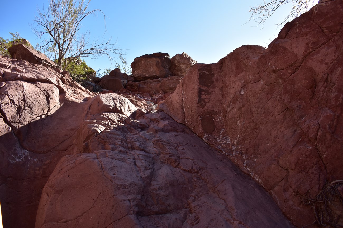 Image of a steep, smooth rock ledge to scramble over on the trail.