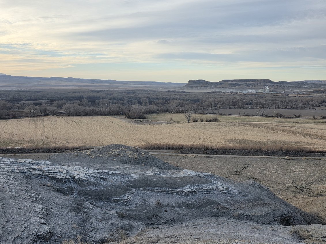An overhead view of an unburned field before the burned area of the Yellowtail Wildlife Habitat Management Area. Mountains and a small plume of smoke in the background.