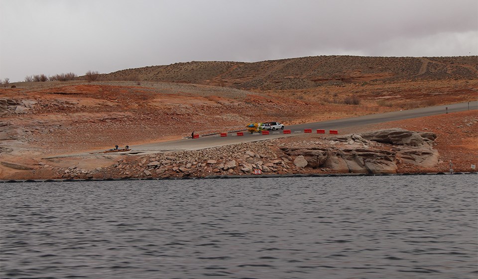 Various kayaks and gear on launch ramp. rocky shelf to water.