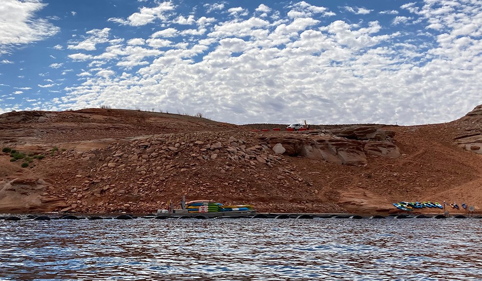 Various kayaks and gear on launch ramp. rocky shelf to water.
