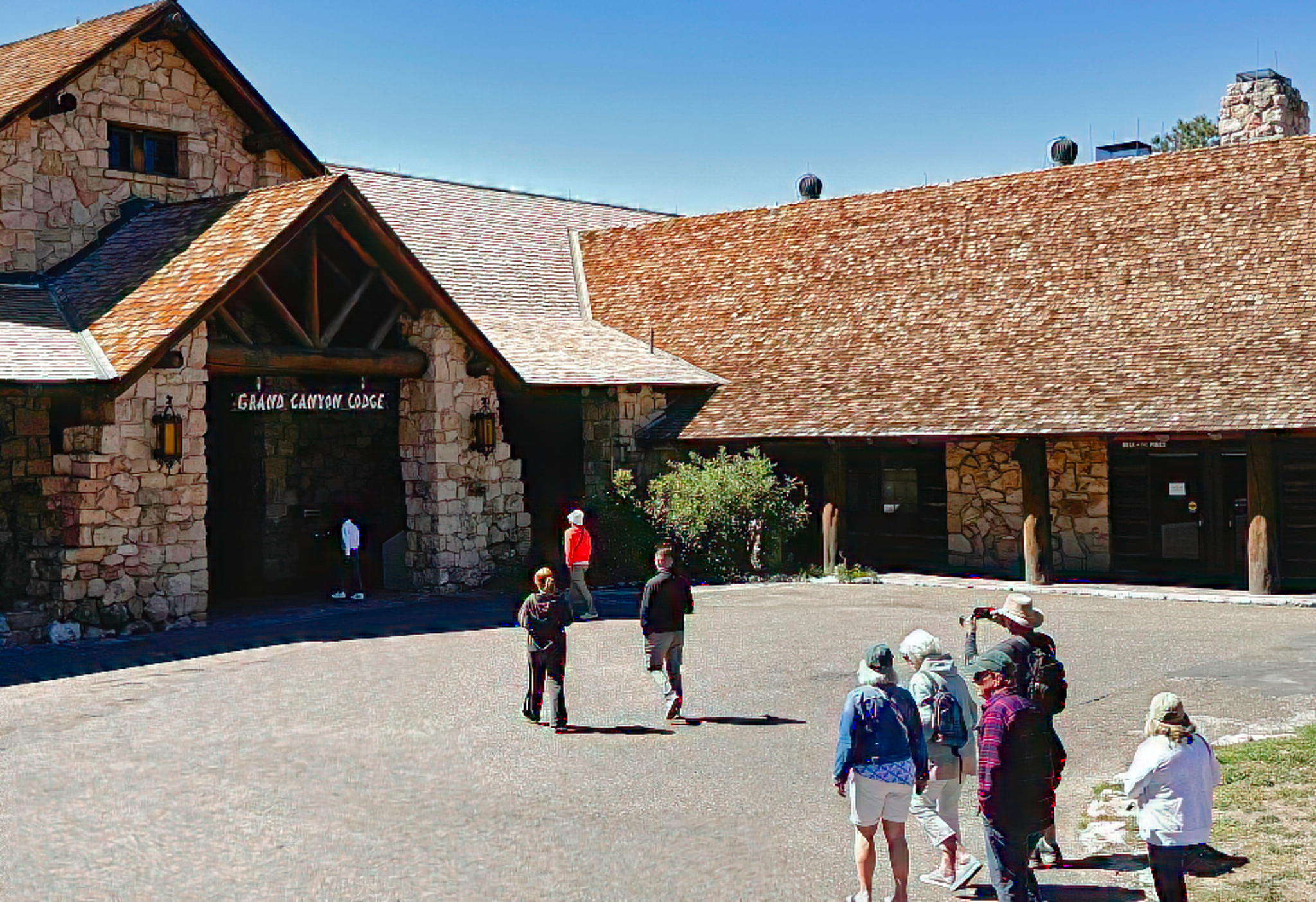 Old cars with group of people lined up in front of hotel building.