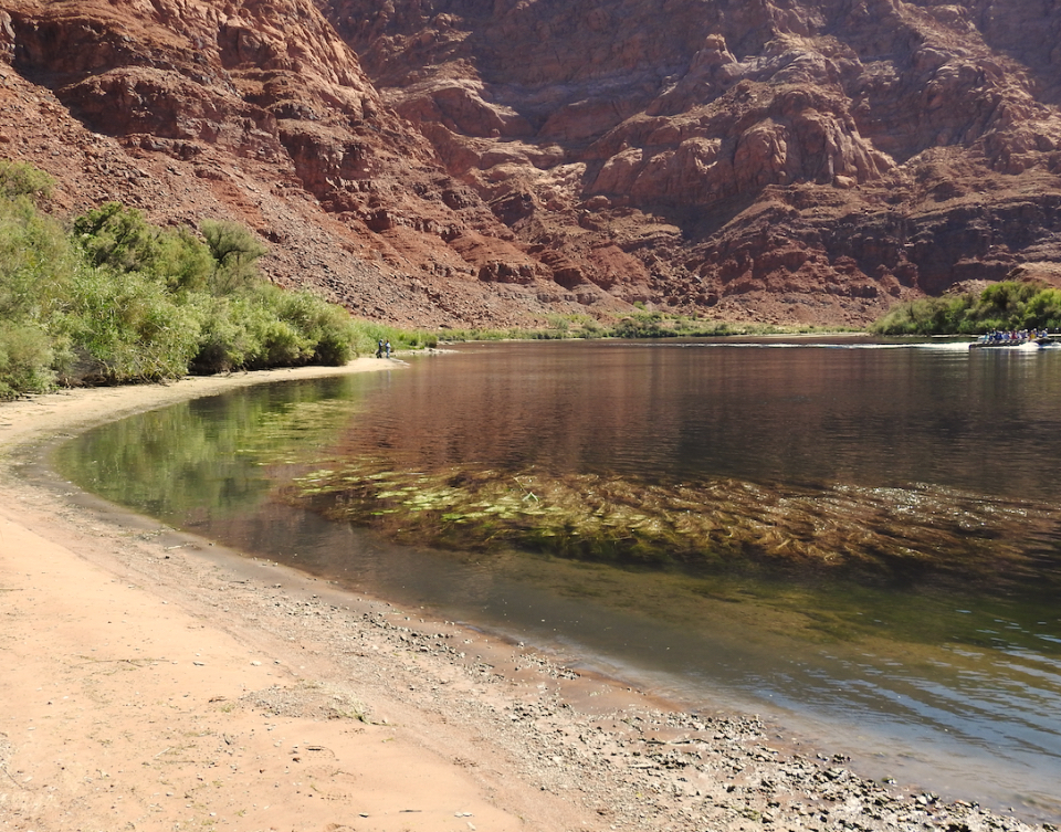 Men and boats on river with cliffs