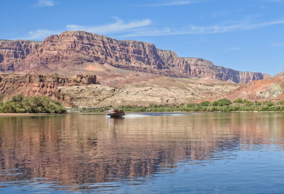 People in boats on river with cliffs and trees