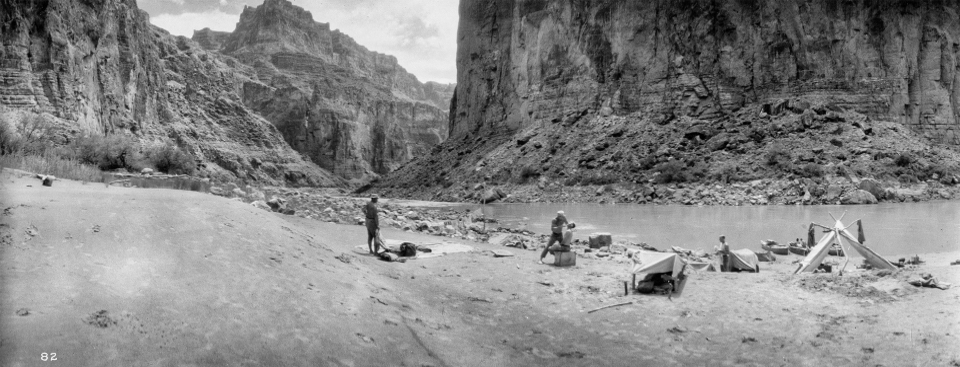 Men on river beach with cliffs