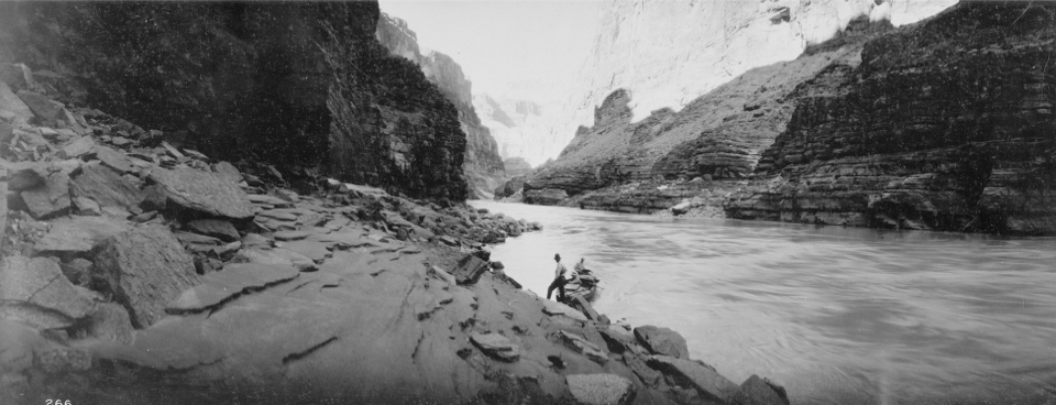 Men with boats on river bank with cliffs in background