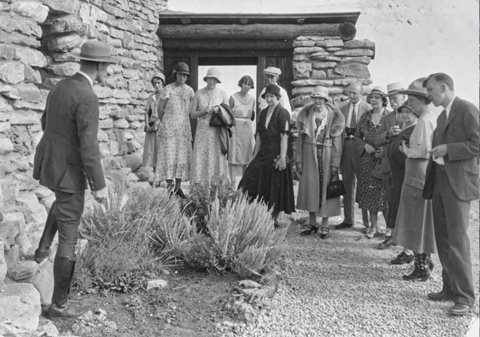 Park ranger speaking to group of people in front of stone building