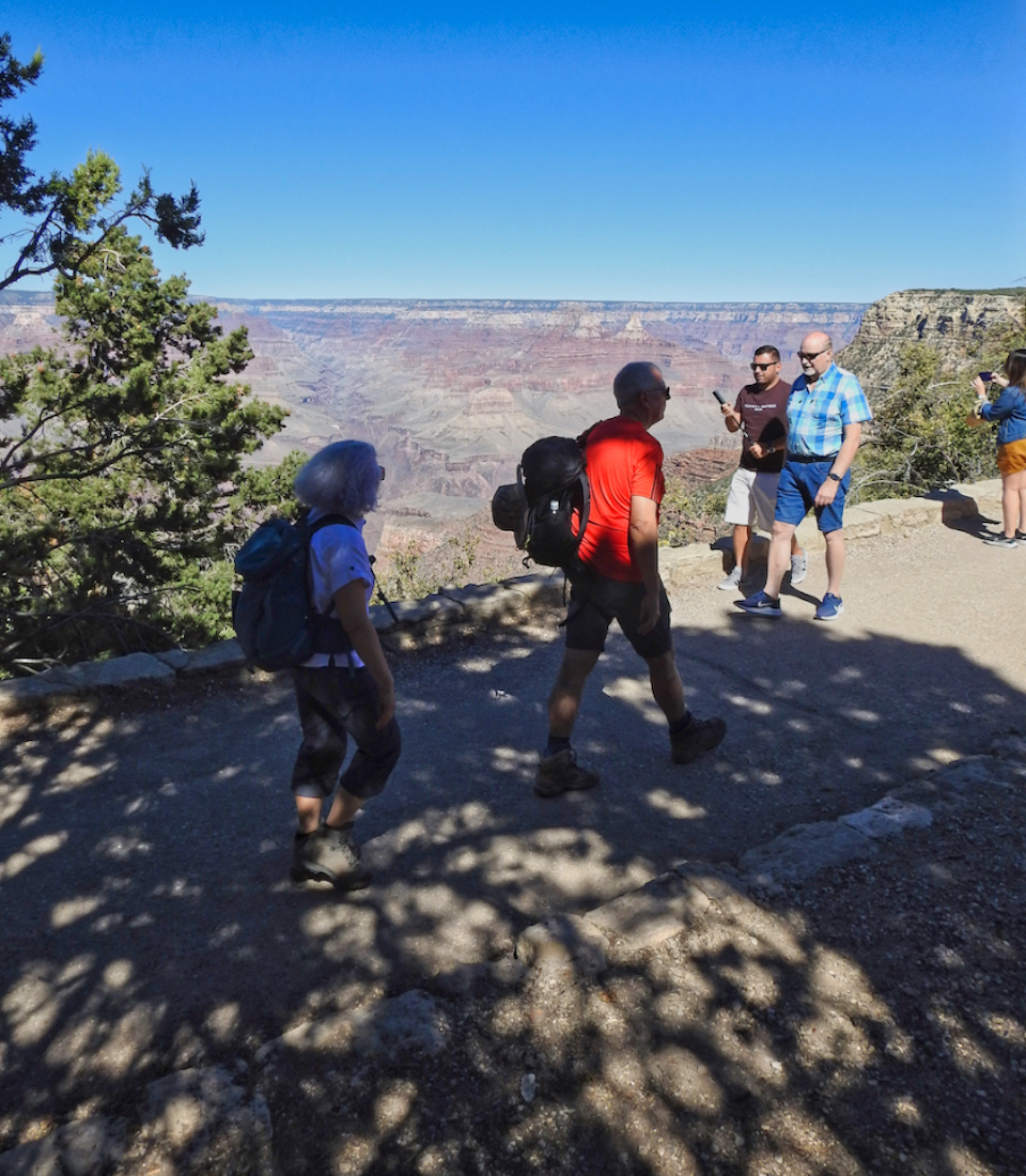 Two men stand on cliff edge with canyon in background