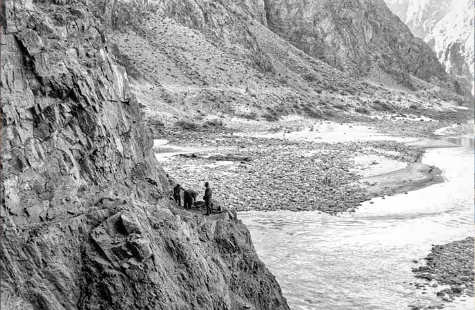 Men on edge of cliff with river in background
