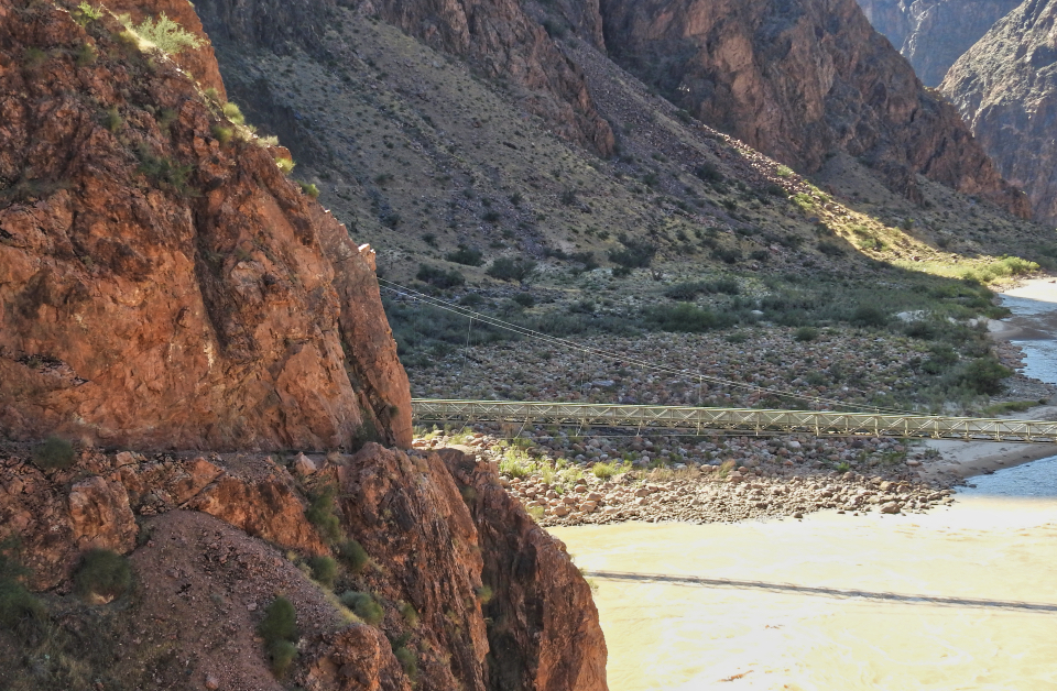 Men on edge of cliff with river in background