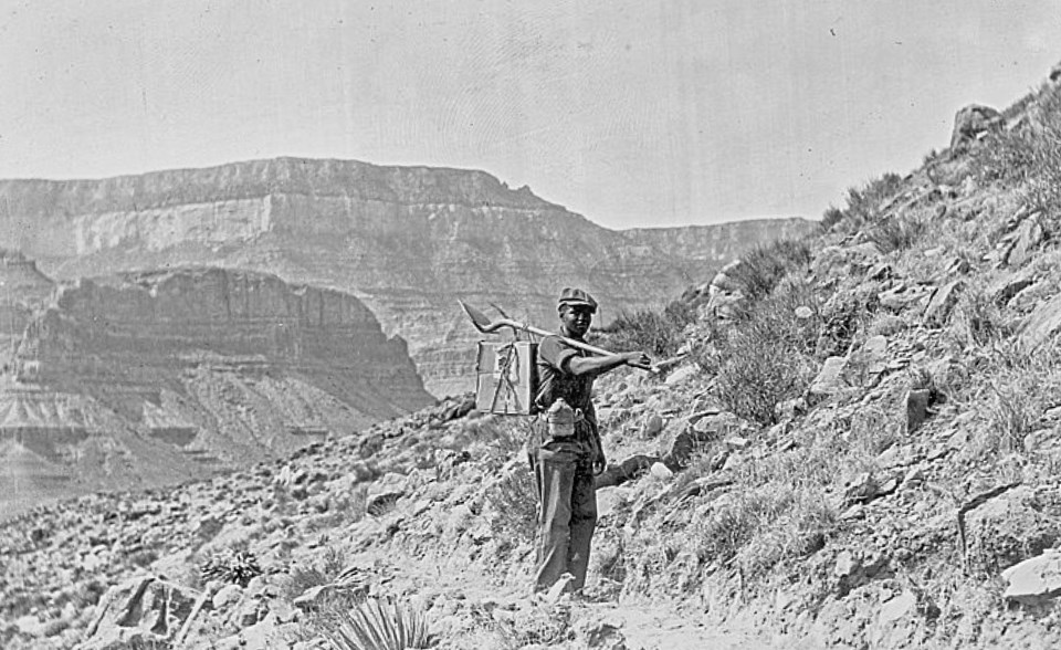 African-American man with shovel on trail with mountains in background