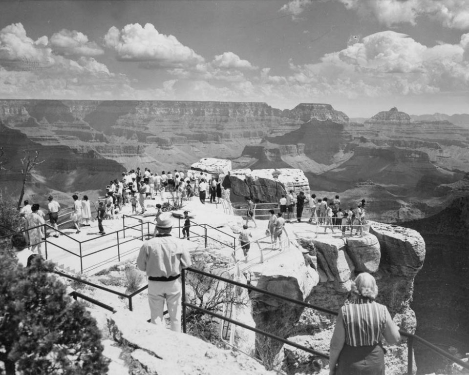 Cliff edges with people, fences, and canyon in background