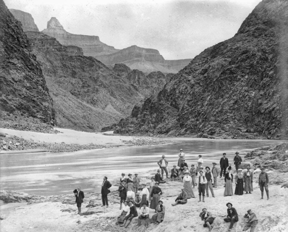 A group of people on the river beach with cliffs in background