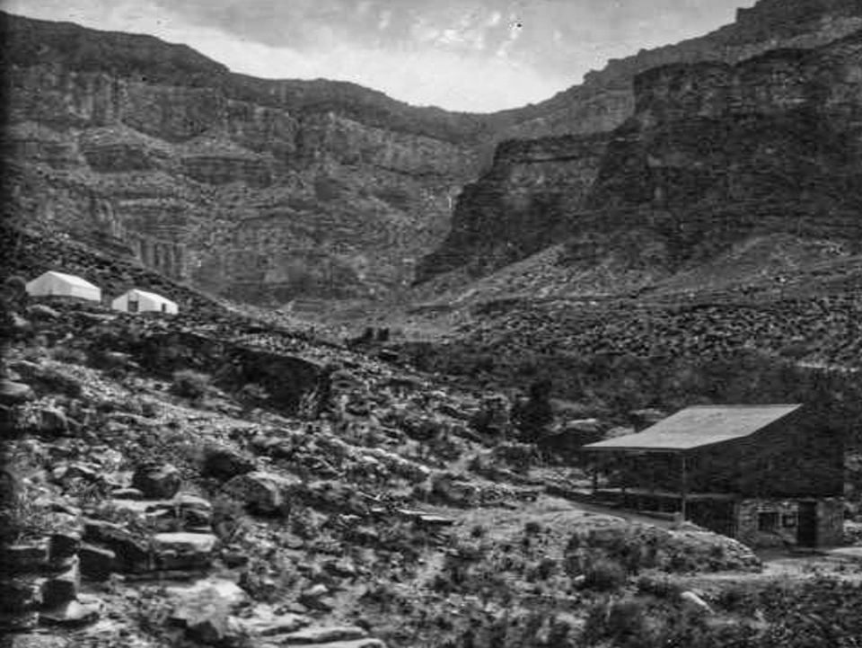 Stone and wood structures on hillside with cliffs in background