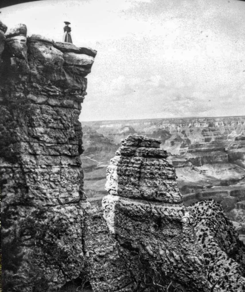Woman standing on edge of cliff with canyon in background