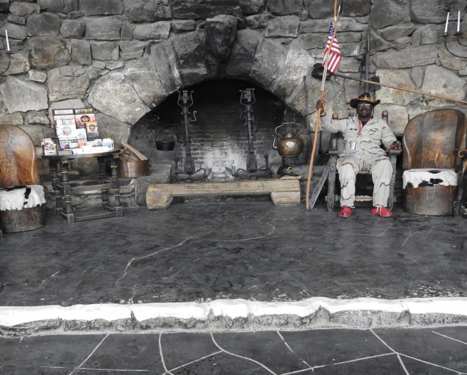 Men sitting in front of stone fireplace with candles and bear rug on floor
