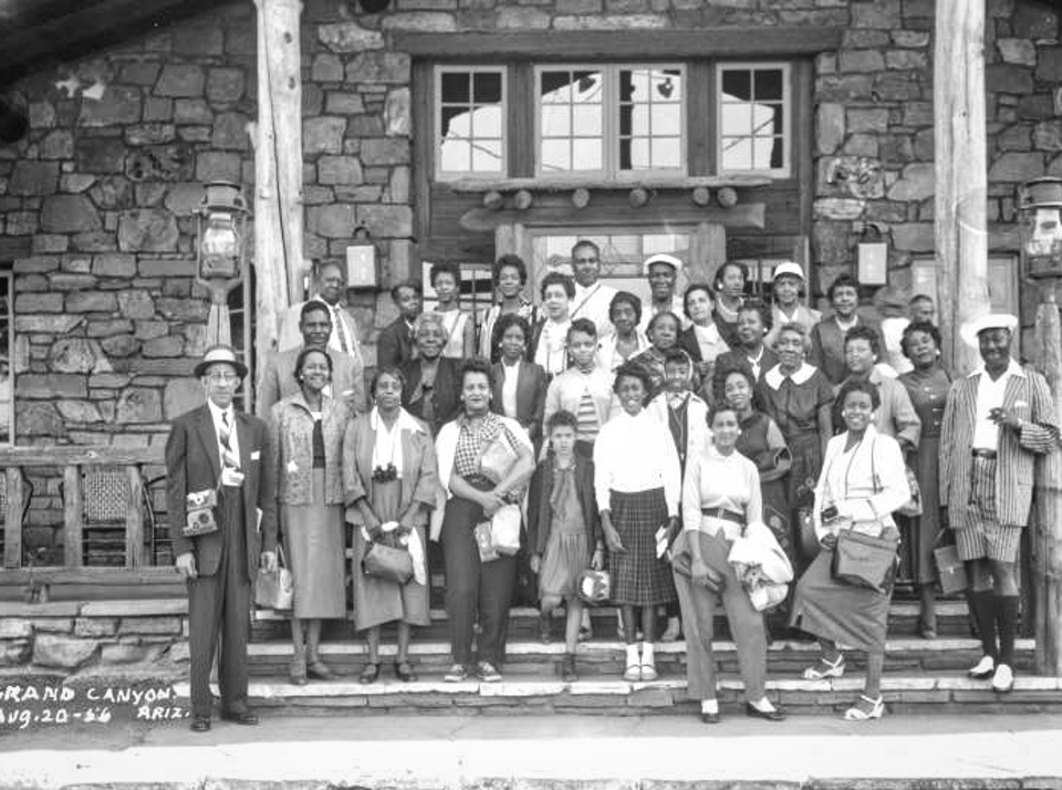 Group of people standing on stairs in front of stone building with windows