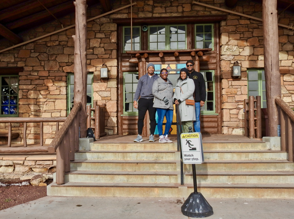 Group of people standing on stairs in front of stone building with windows