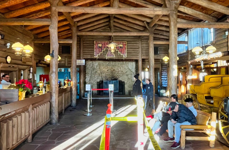 Colorized postcard of hotel lobby with wood beams, people and furniture