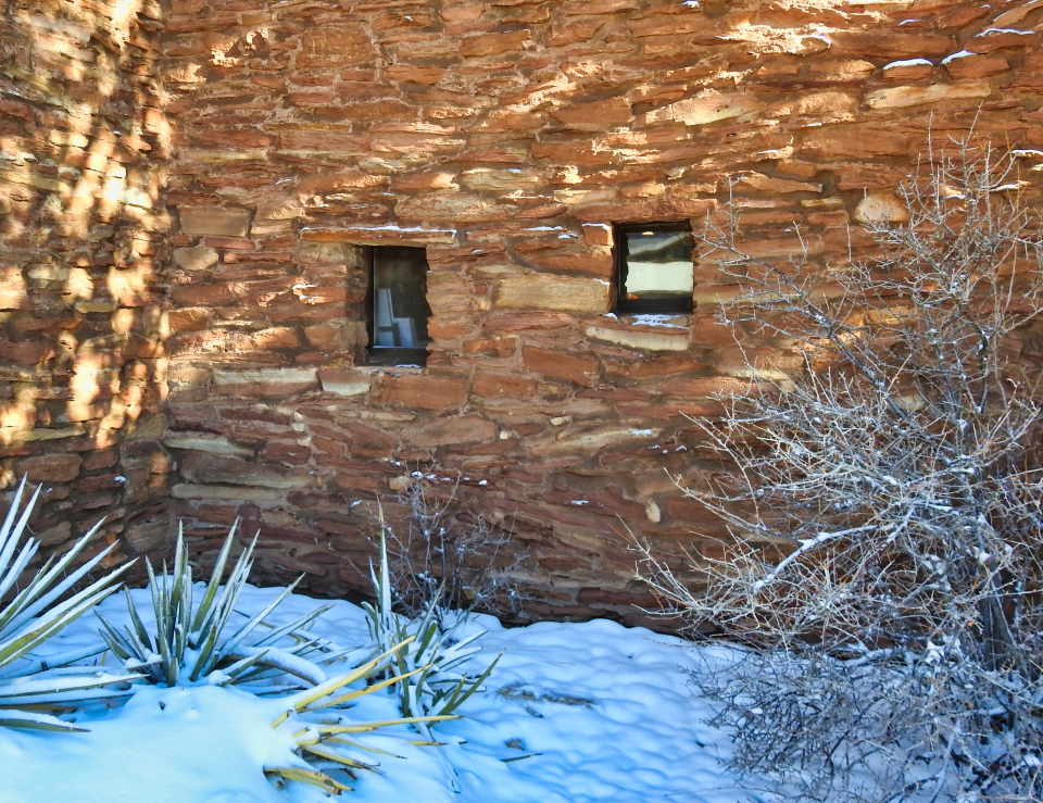 6 people stand in front of stone building, most dressed in tribal clothing