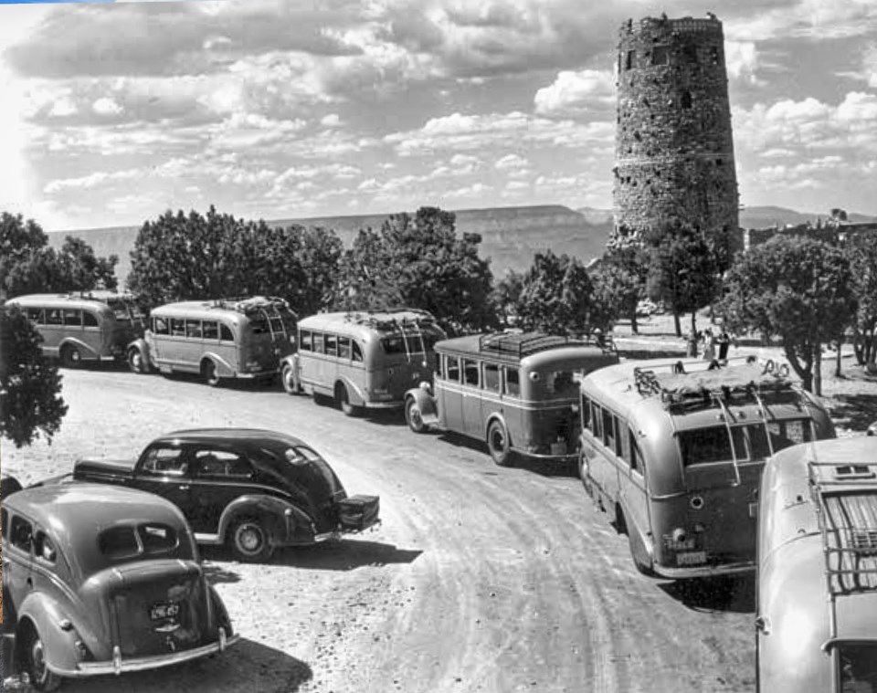 Buses and cars on road with stone tower in background