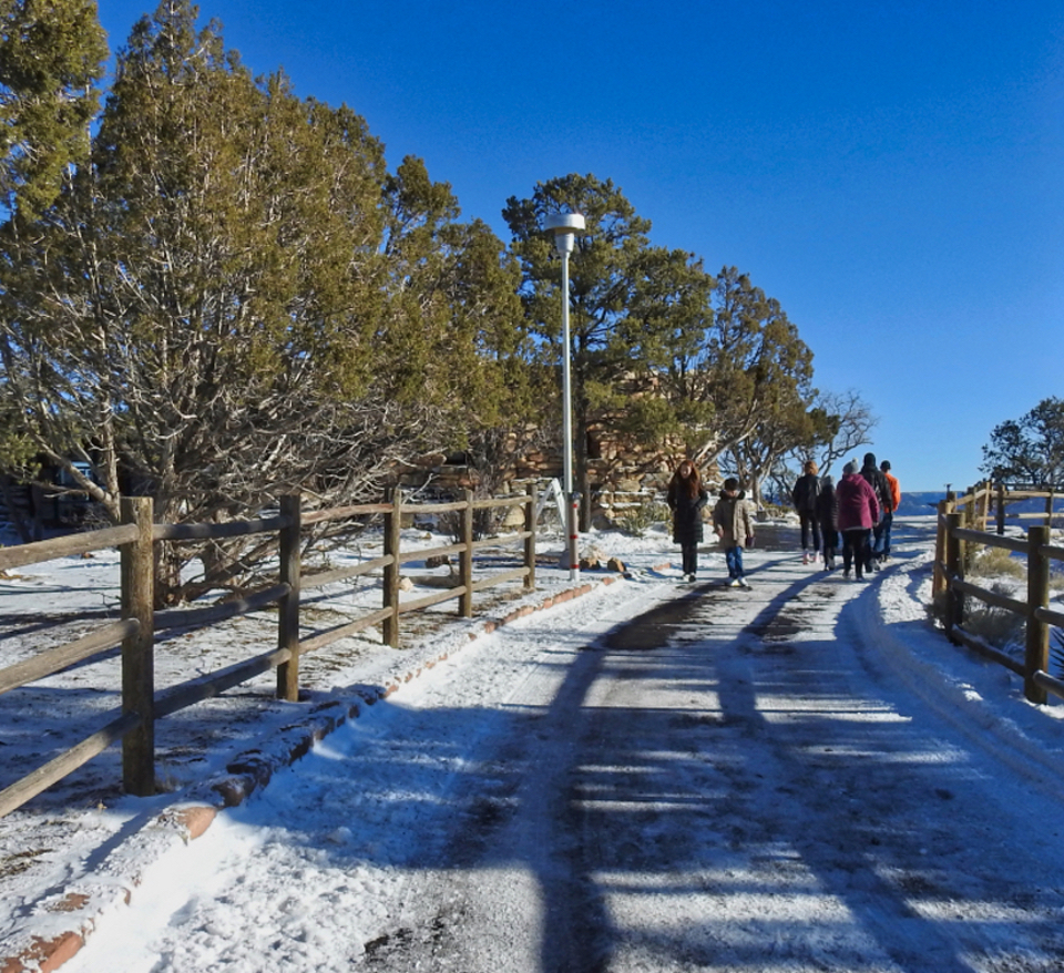 People and a line of old cars on road with stone building in background
