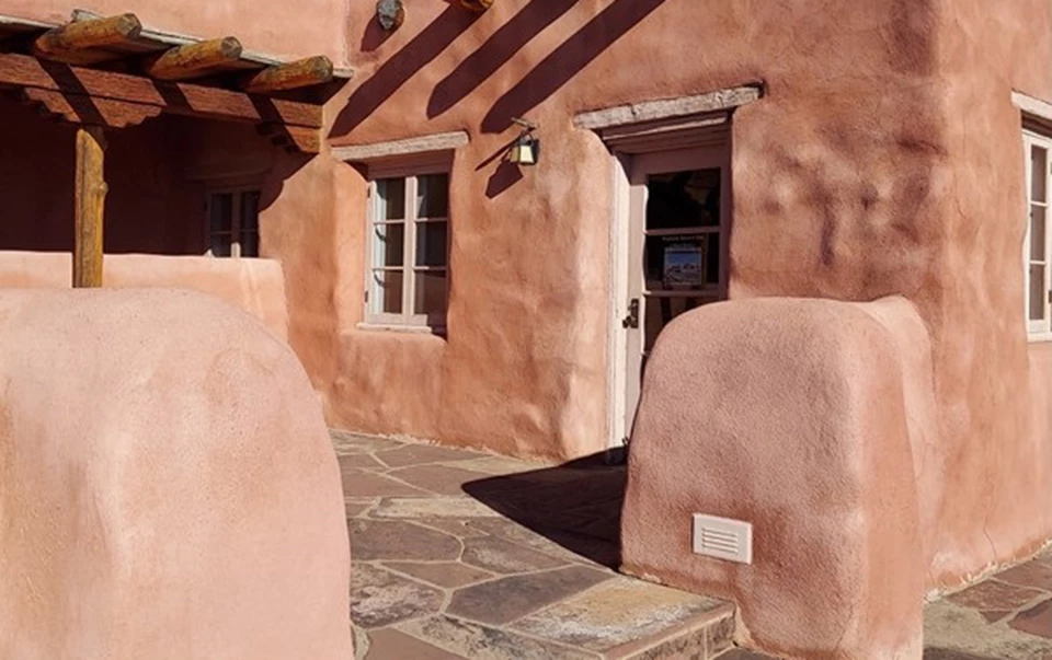 Old photo with girl in dark coat in front of a pueblo style building