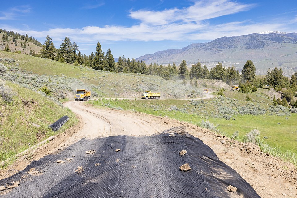 Single land dirt road with dump trucks