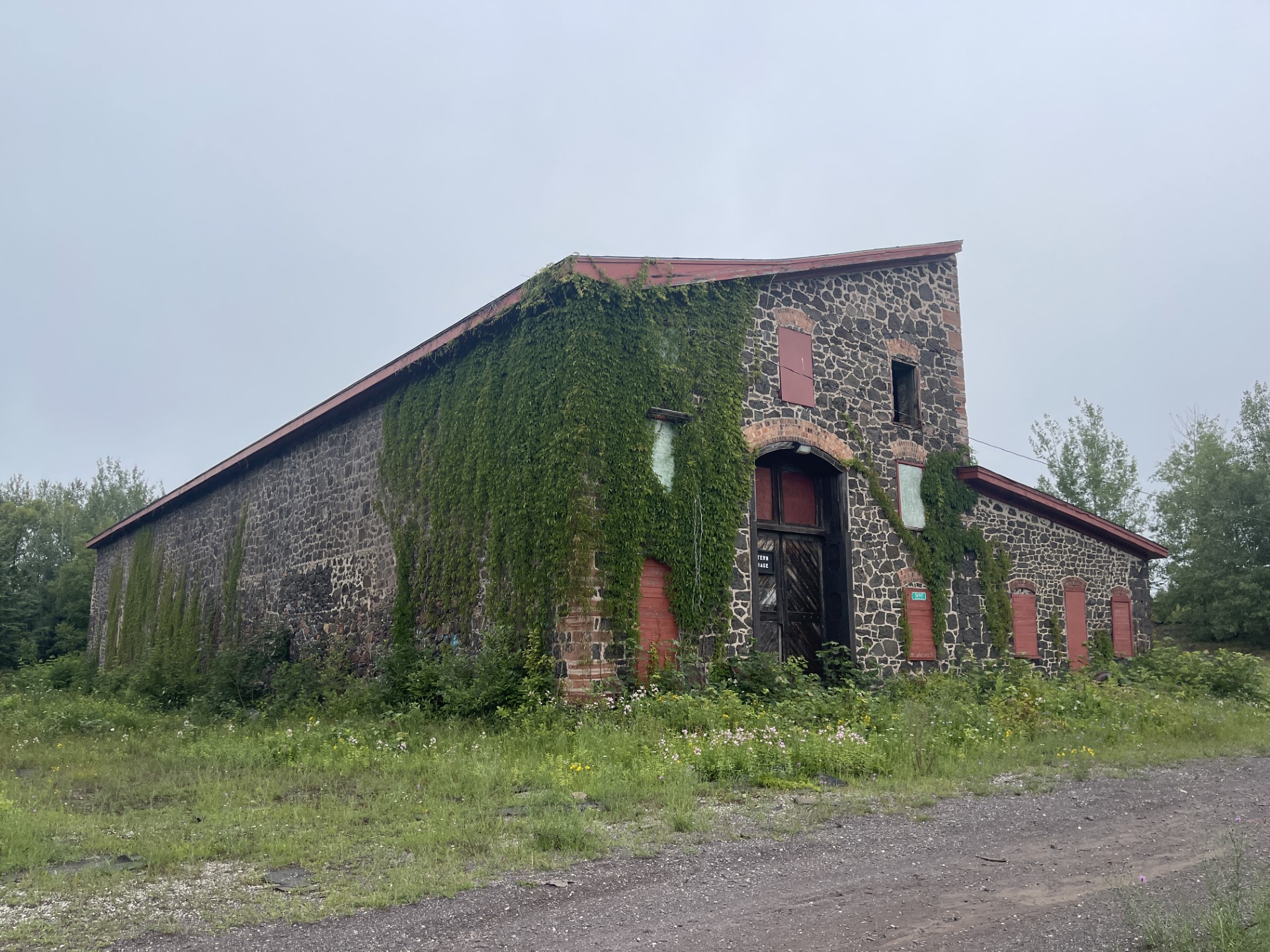 A stone building with red windows. Green vines stretch from ground to roof.