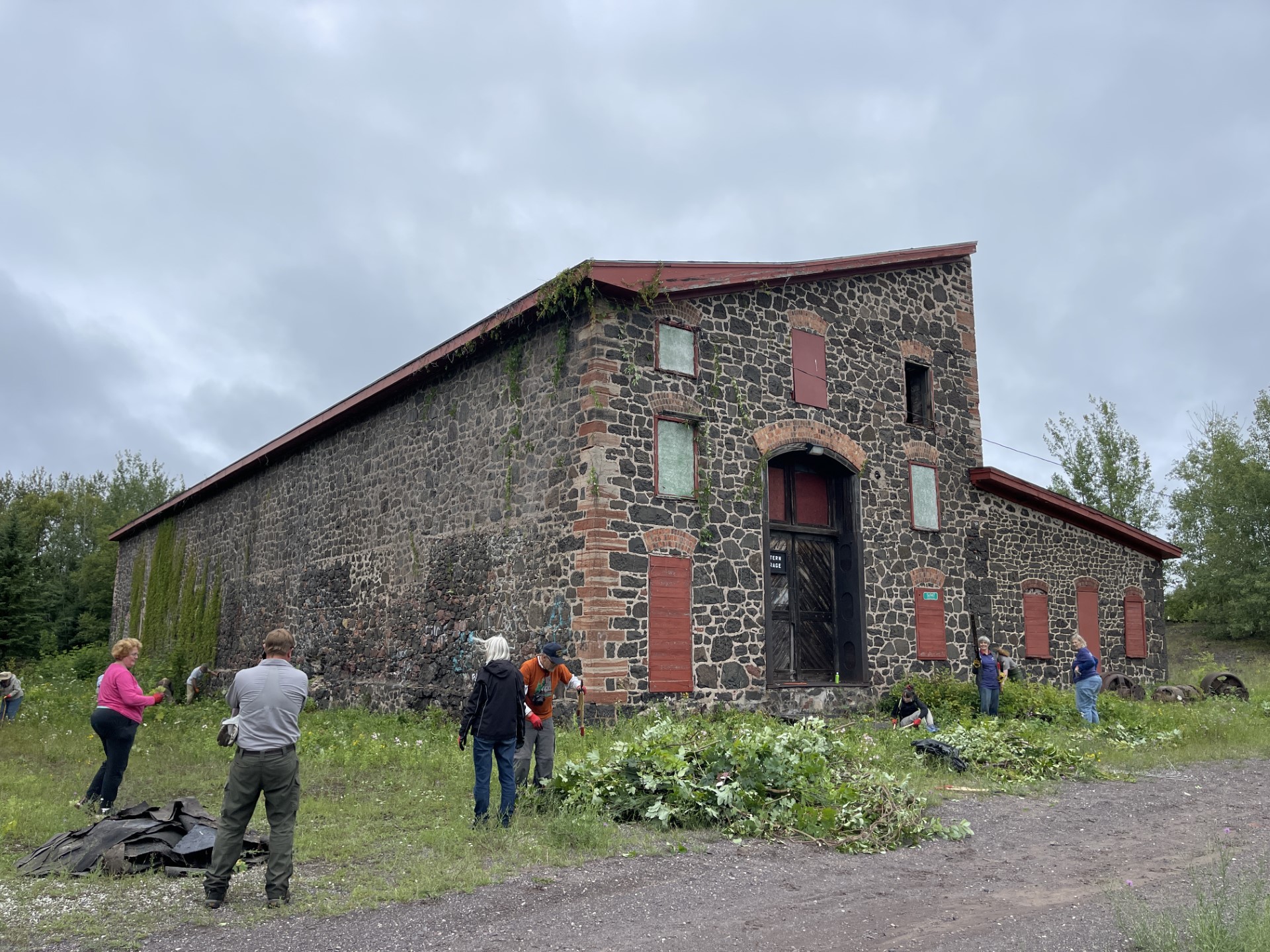 A stone building with red windows. Green vines stretch from ground to roof.
