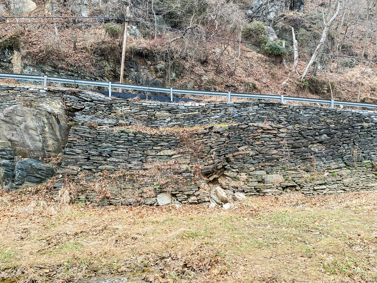 A sagging stone wall holding up a road