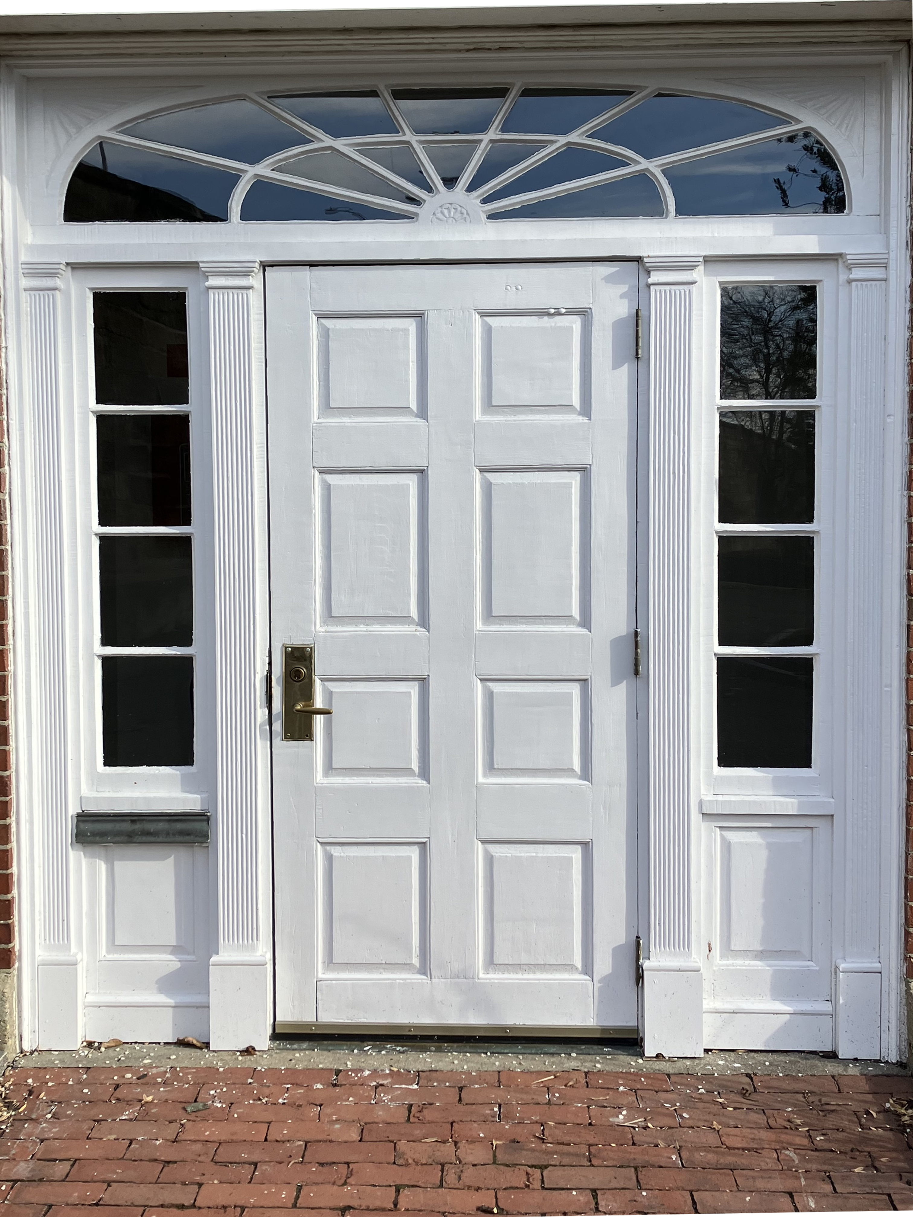 A large white door with top and two glass side panels in worn condition.