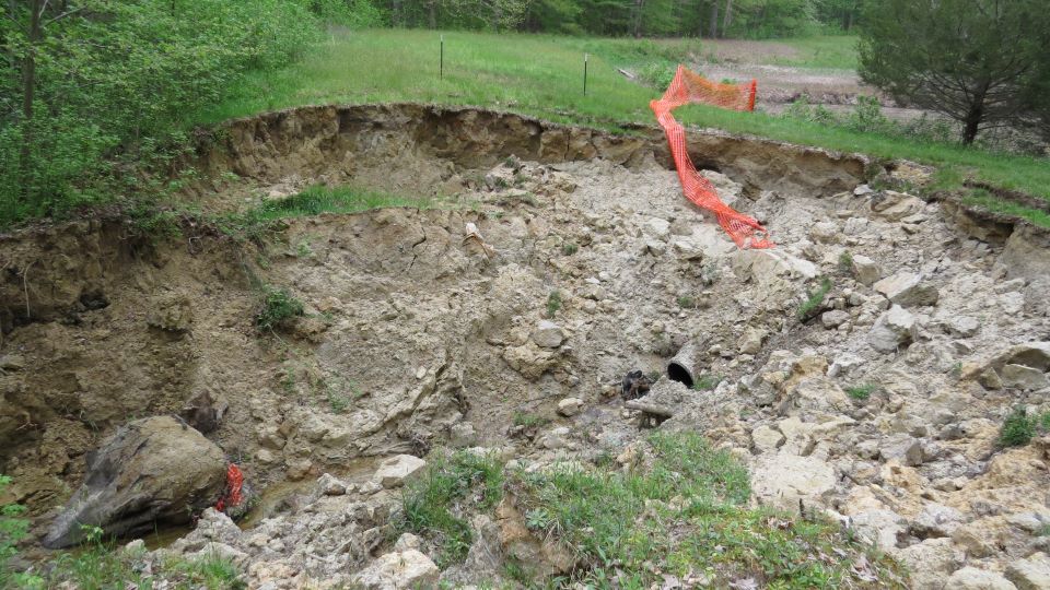 A large sinkhole in a grassy lawn