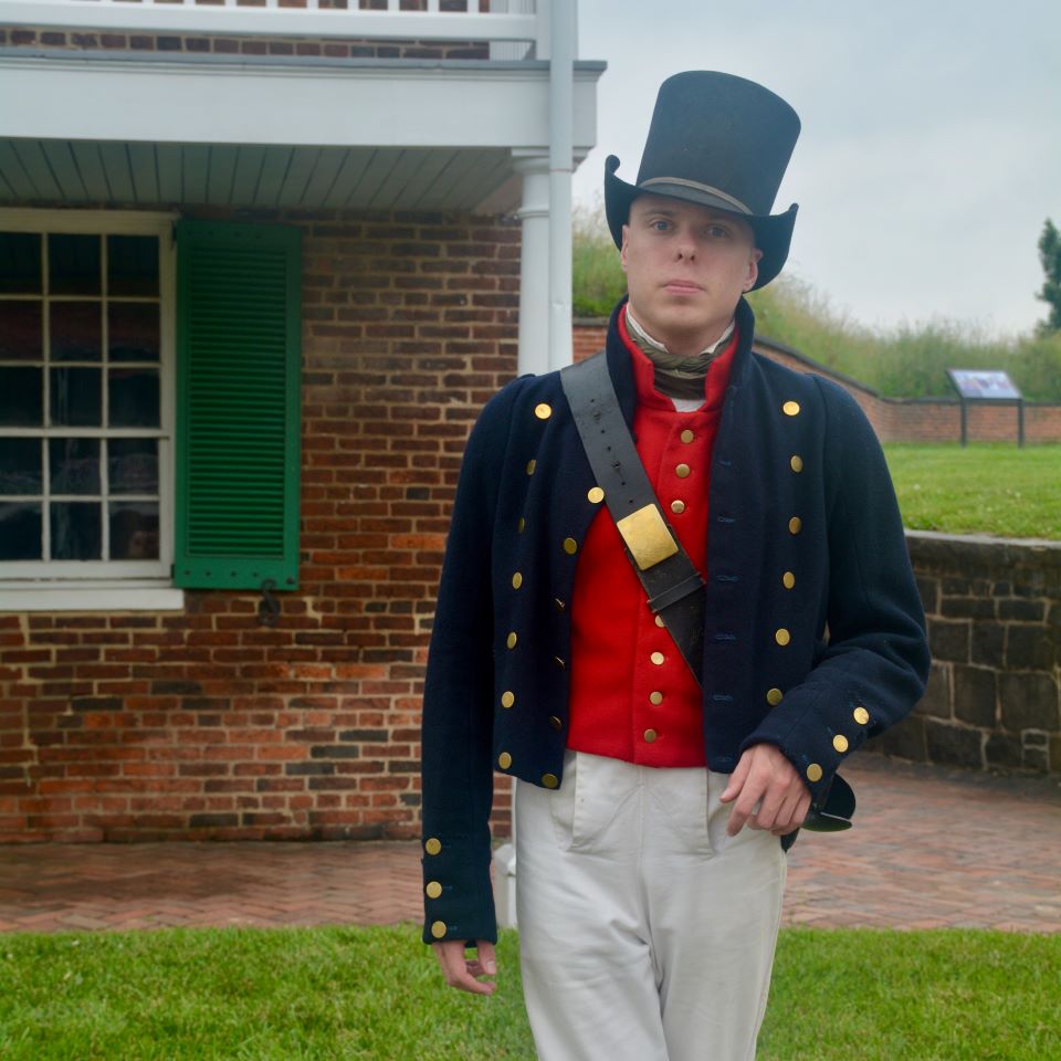 WWI soldier in front of buildings that may have served as hospital buildings at Fort McHenry during its time as a WWI hospital.