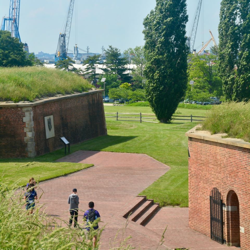 A procession of nurses march in to the SallyPort of Fort McHenry, as rows of soldiers wait and watch for their turn to proceed in.